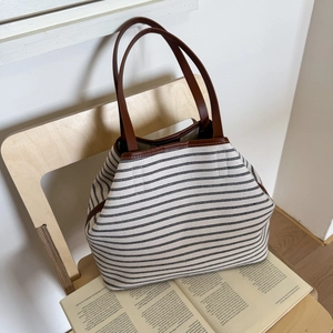 Minimalist striped canvas tote bag with brown leather handles and casual aesthetic
