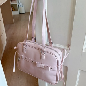 Close-up of pink JK style handbag with bow decoration and silver heart charm details