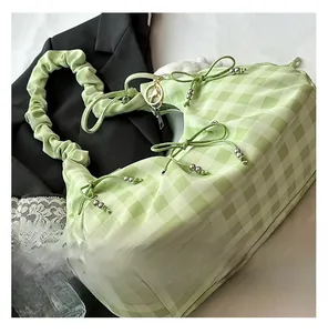Dettaglio borsa a quadretti verde chiaro con fiocchi, perline argentate e tracolla arricciata