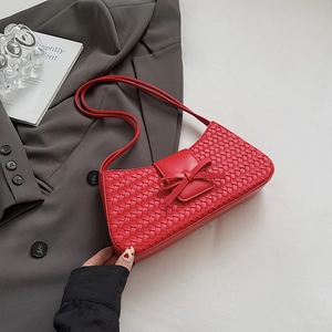 Détail du sac baguette rouge tissé avec nœud en cuir et texture en damier élégante