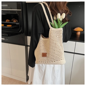 Close-up of beige crochet tote bag featuring hollow out grid pattern and leather patch