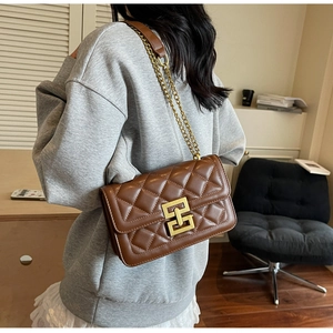 Gros plan du sac bandoulière matelassé marron avec chaîne dorée et fermoir géométrique chic