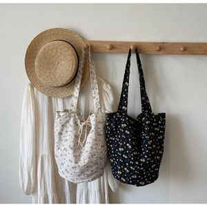 Detailed close-up of floral canvas tote bags featuring drawstring closure and cotton linen texture