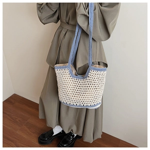 Detail of hollow woven cotton shoulder bag with blue trim on a model for beach vacation