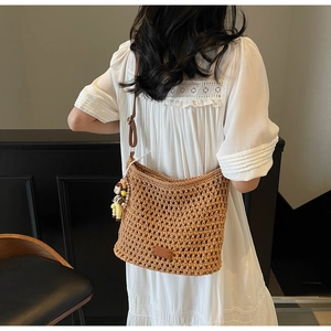 Detailed macro view of brown crochet hollow-out tote bag texture with cute doll charm