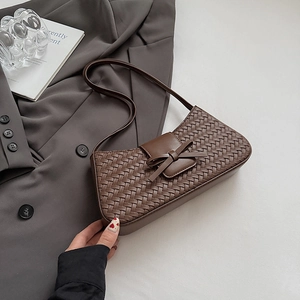 Détail d'un sac baguette tressé marron avec nœud en cuir élégant et bandoulière