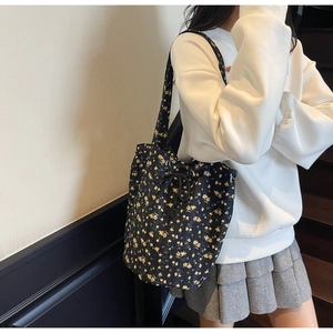 Lifestyle view of floral canvas tote bag with drawstring closure on model in stairwell