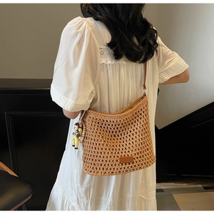 Detail of a brown woven hollow beach tote with fine mesh texture and a cute charm