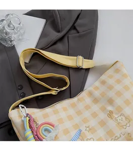 Détail de la bandoulière large réglable et de la broderie d'ours sur le sac à carreaux