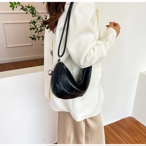 Détail du sac à bandoulière croissant noir avec pendentif boule argentée et cuir brillant