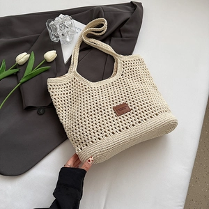 Close-up of beige crochet woven tote bag featuring honeycomb texture and brown leather logo tag