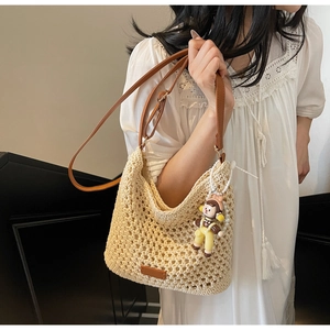 Detail of woven beach tote with brown leather strap and cute character charm