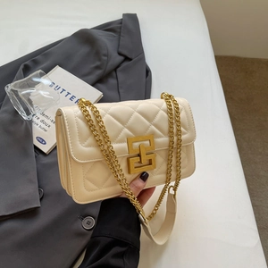 Détail de sac à main matelassé crème avec fermoir géométrique doré et bandoulière chaîne