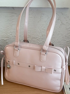 Pink JK style PU leather tote bag with bow detail and heart pendant on white background