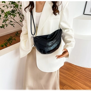 Détail du sac bandoulière croissant noir en cuir verni brillant avec breloque argentée