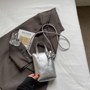 Detailed macro view of a metallic silver bucket bag with elegant metal ball charm and strap