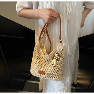 Detailed close-up of woven hollow beach tote with adjustable brown leather strap and charm