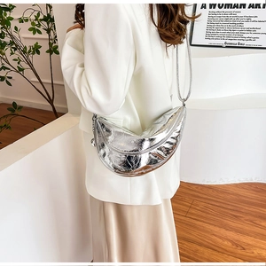 Sac croissant argenté chic avec texture métallique sur mannequin en costume blanc
