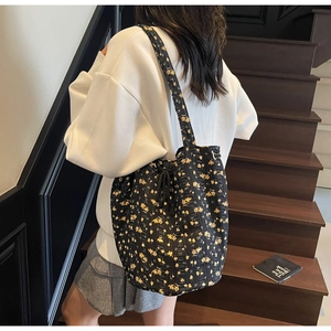 Detail of floral canvas tote bag showing black fabric with yellow flowers and drawstring side