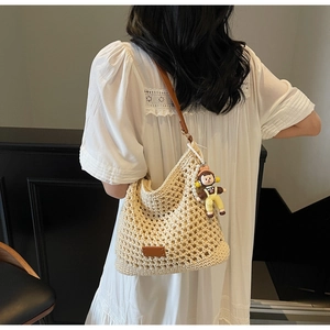 Detail of hollow woven shoulder bag in beige with brown leather strap and cute doll