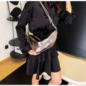 Sac bandoulière plissé métallisé argenté porté avec une robe en satin noir élégante