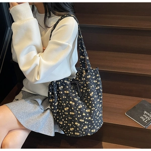 Detail of black floral quilted tote bag with yellow flowers and drawstring closure