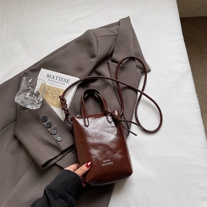 Detailed macro view of the glossy dark brown mini bucket bag with AIYAN brand lettering