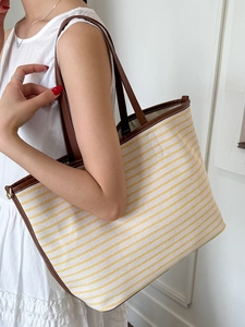 Large capacity canvas tote bag with yellow stripes and brown leather handles on model