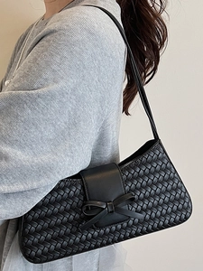 Sac baguette noir tressé chic avec nœud en cuir pour femme porté par un mannequin