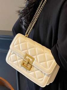 Sac à bandoulière matelassé crème avec chaîne dorée porté par un mannequin en noir