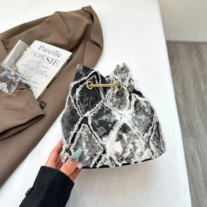 Distressed denim bucket bag with quilted patterns and fringe detail in snowflake gray