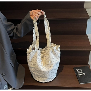 Detail view of floral drawstring bucket bag with pleated fabric texture and purple patterns