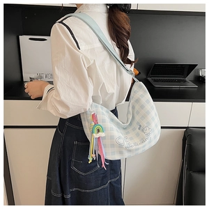 Détail du sac bandoulière à carreaux bleus avec broderie et breloque arc-en-ciel