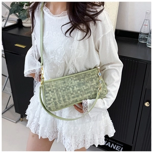 Close-up of light green woven underarm bag with gold hardware and star charm details