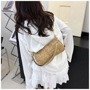Detail view of khaki woven baguette bag with adjustable strap and gold metal hardware