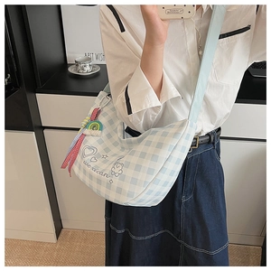 Détail du sac croissant à carreaux bleus avec broderie et pendentif coloré