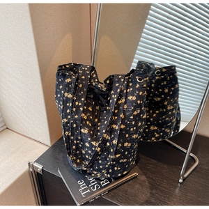 Close-up of floral canvas bucket bag with yellow flowers, drawstring and metal eyelets