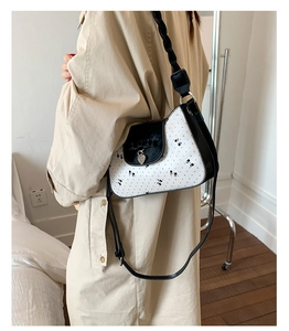 Détail du sac bandoulière français avec pendentif cœur et motifs nœuds élégants