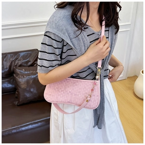 Close-up of pink woven checkerboard underarm bag with flower and pearl charm detail