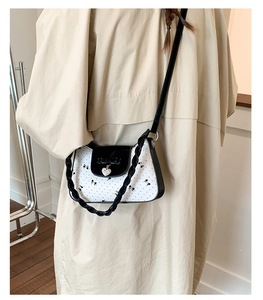 Vue détaillée du sac à pois blancs avec un nœud noir et un pendentif en forme de cœur argent