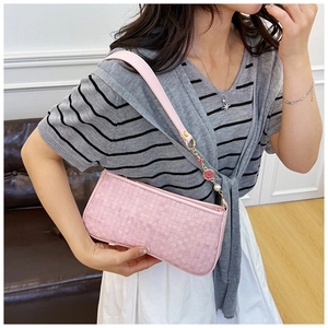 Close-up of pink woven checkerboard baguette bag with floral pearl charm detail