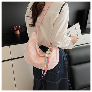 Sac à carreaux rose avec textures cœurs et pompon arc-en-ciel porté par le modèle