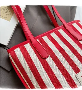 Detailed view showing the red striped canvas texture and fine stitching on the tote bag