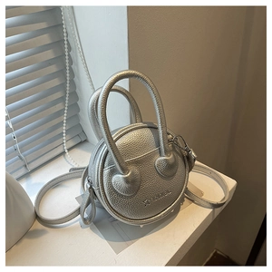 Detail view of silver round mini crossbody bag featuring textured lychee pattern leather