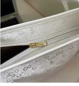 Détail d'une fermeture éclair dorée lisse et texture embossée sur un grand sac cabas