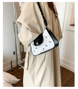 Détail du sac à bandoulière blanc à motif papillon avec bordure noire et pendentif cœur