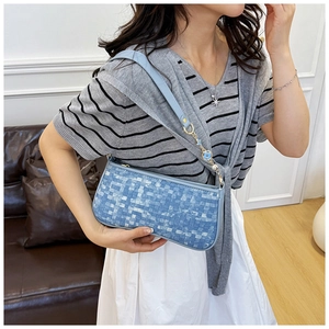 Detail of light blue checkered underarm bag with floral charms and gold hardware