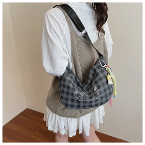 Détail du sac hobo à carreaux gris avec broderies et bandoulière en cuir noir