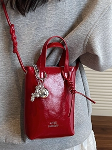 Mini red patent leather bucket bag with silver balloon dog charm and knotted strap