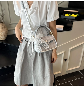 Detail view of stylish grey crossbody bag with lace bow and plaid flap on stairs